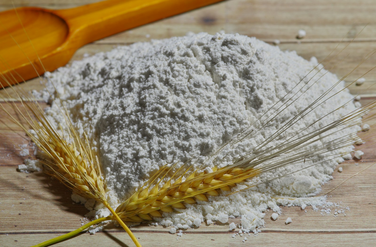 Făină albă de grâu și spice de grâu pe masă din lemn